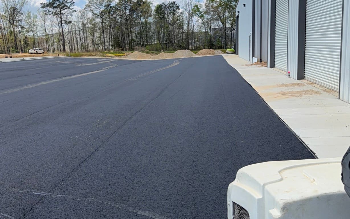 Fresh asphalt mat rolled out beside a commercial storage building by Ford Paving