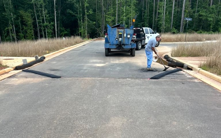 Ford Paving crew member applying sealer on a neighborhood street