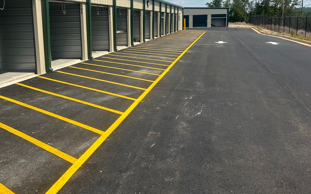 Fresh yellow parking stalls and directional arrows striped at a storage facility
